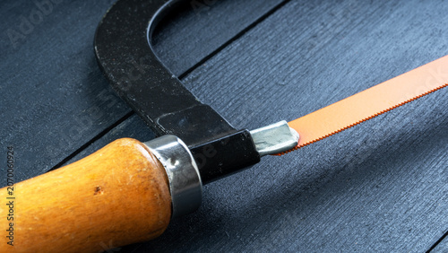 Fotografie Handy saw rests on dark textured surface