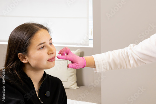 Obraz na plátně A picture of a very beautiful and attractive young lady showing the process of a lip rejuvenation procedure, in a professionally arranged office