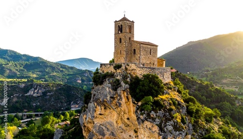 A stone structure crowns a rocky peak, bathed in golden sunlight. Lush greenery surrounds the tower against a backdrop of rolling hills