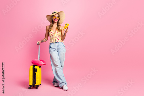 Konstfotografi Young stylish woman with yellow suitcase wearing hat and sunglasses posing for t