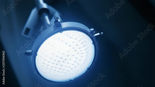 Operating room lamp casts intense bright blue light onto a surgical area, creating a sterile and focused environment for medical treatment and critical procedures