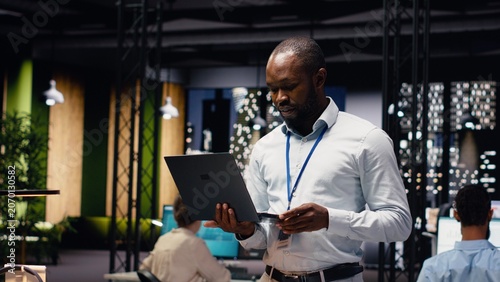 Fotografie Portrait of black businessman in office managing schedules on laptop, organizing calendar appointments and meetings, male entrepreneur ensuring profitability with company records
