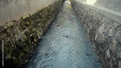 Polluted Water Flowing Through Stone Channel With Mossy Walls And Gray Murky Texture