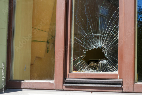 фотографія Broken Residential Window With Large Impact Hole and Cracked Glass After Vandali