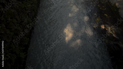 Tilt Up View Of Gray Water Flowing Through Concrete Drainage Ditch With Mossy Walls And Daylight