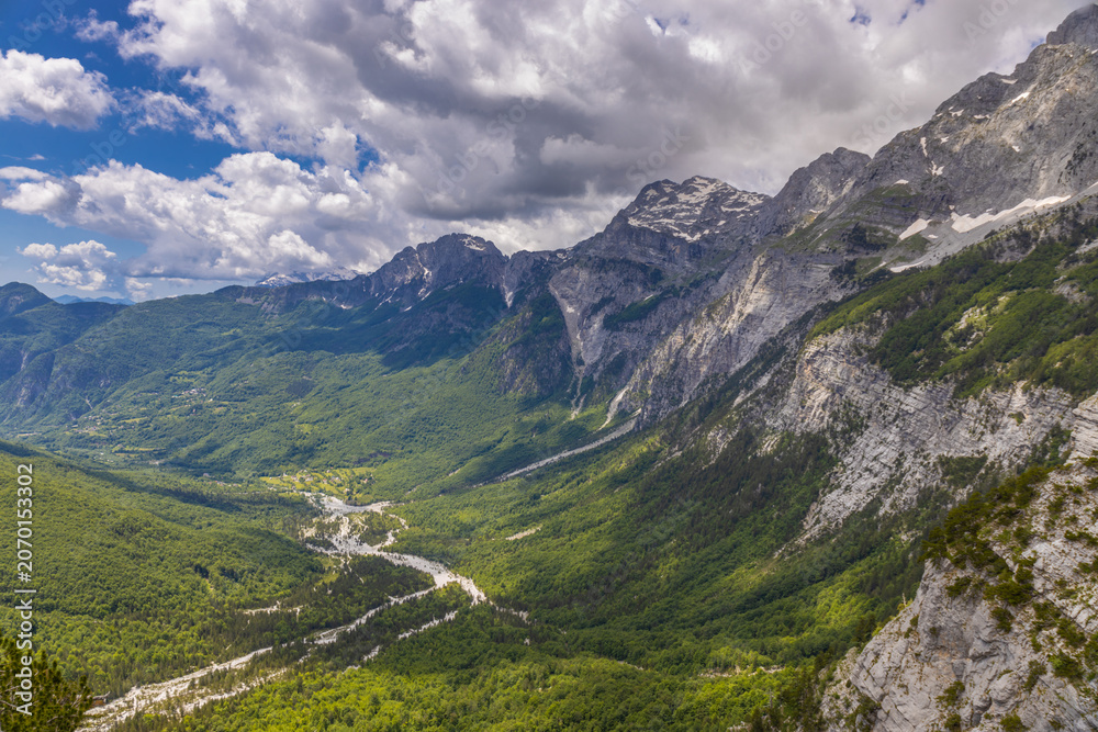 Fototapeta premium Mountain landscape in the Albanian Alps near Theth, Albania. Theth Valbona valley trek Peaks of the Balkans scenic way. Rugged peaks rise above forested valleys and alpine meadows