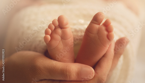 Adult hands gently holding tiny newborn baby feet