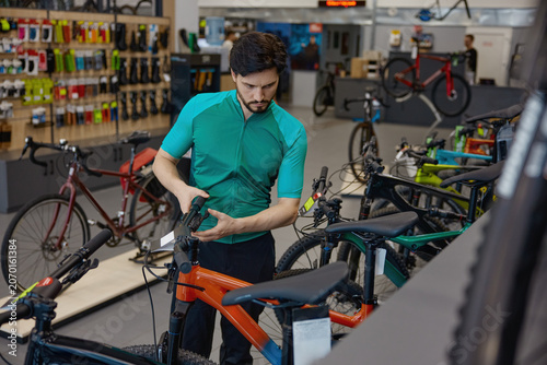 Product consultant prepares for test ride amidst neatly arranged bicycles and retail environment