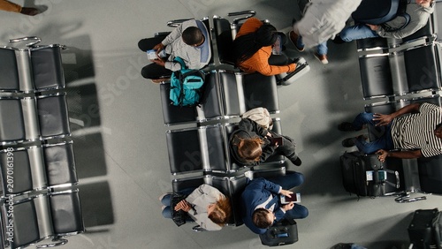 Tableau sur toile Holding travel documents, top down view and passengers crowd in busy airport terminal, Looking at plane tickets, long flight layover and high angle shot of group of people