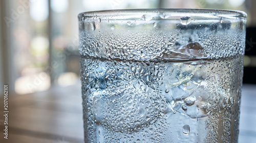 Close-up of a glass of sparkling water with bubbles on a wooden table