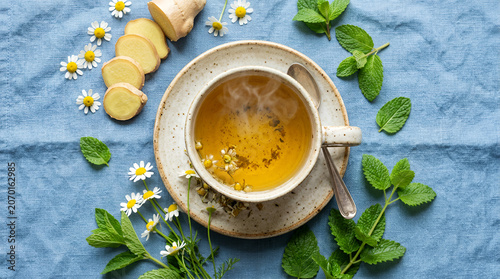 Herbal tea with flowers and ginger on a blue tablecloth with natural ingredients
