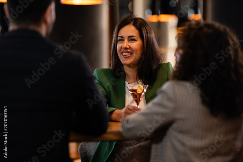 Woman socializing with friends enjoying cocktails in bar
