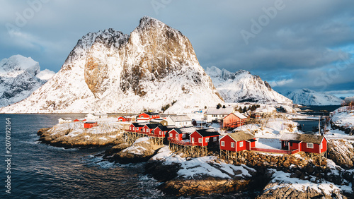 Fotografie Red rorbuer cabins below dramatic winter peaks in Hamnoy, Lofoten Islands, Norwa