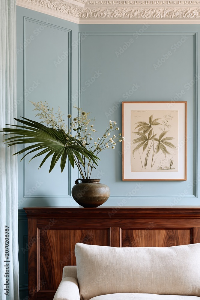 Fototapeta premium Living room corner featuring a dark walnut mantelpiece with a decorative vase of flowers and a botanical print on the blue wall, creating a serene interior design aesthetic