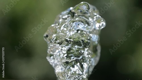 Water jet. Top of water fountain. Flow of pure spring water on a green natural background.