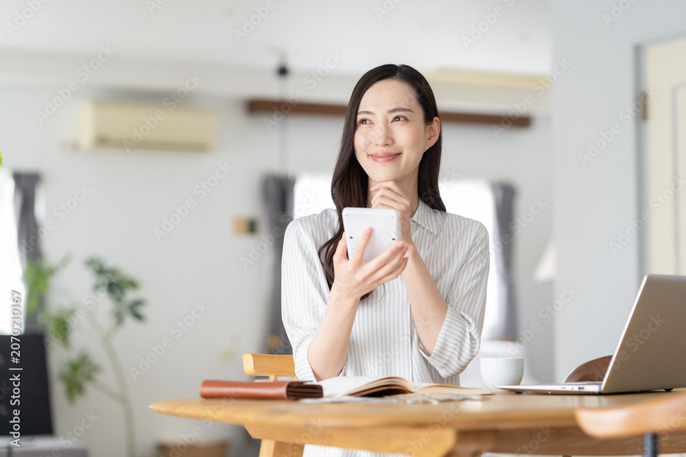 Naklejka premium リビングで家計簿をつけるミドルの女性