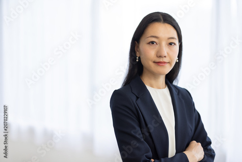 Fotografía Young Japanese businesswoman arms crossed smiling at camera by window