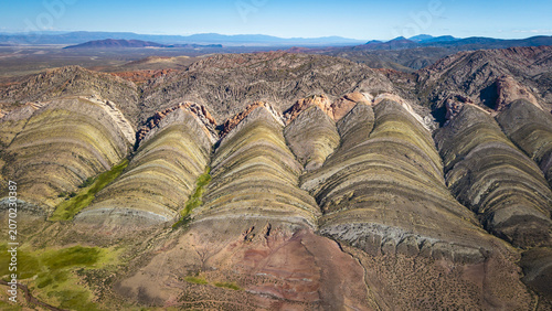 Aerial view of the colorful striated rock formations of Gigantes Dormidos with vibrant mineral layers and arid terrain in Tres Cruces, Jujuy Province, Argentina.