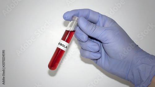 Gloved hand holding test tube with red liquid and ebola label
