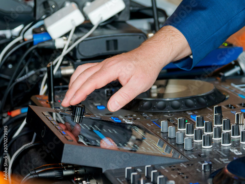 Main d’un DJ réglant une console de mixage lors d’une soirée privée ou d’un événement festif