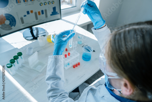 Photos A researcher in a white lab coat performs scientific experiments with liquid samples in a bright laboratory