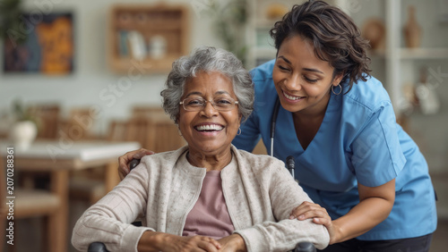 Smiling senior black woman in wheelchair with female caretaker in nursing home. Both women look happy, showing care, companionship, support