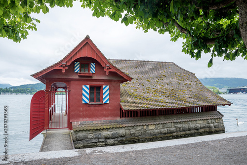 Foto red boathouse with striped shutters, lakeside Lucerne, switzerland