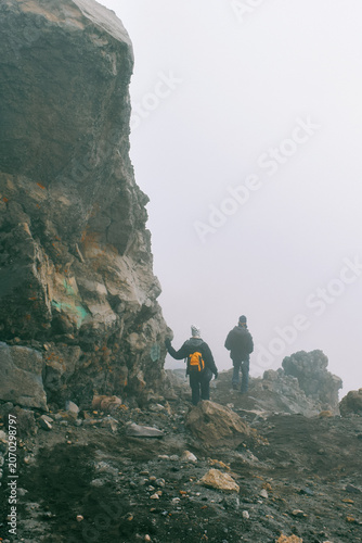 A Group of Hikers Standing on the Volcanic Rim above the clouds on a foggy day in the Alpine Desert Zone of Mount Meru, Arusha National Park, Tanzania