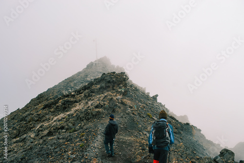 A Group of Hikers Standing on the Volcanic Rim above the clouds on a foggy day in the Alpine Desert Zone of Mount Meru, Arusha National Park, Tanzania