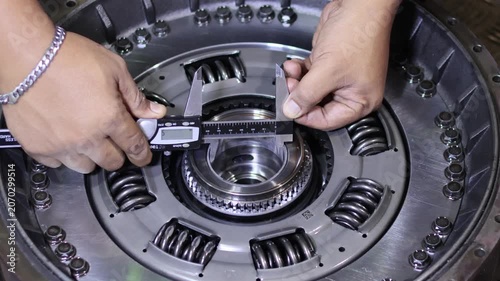 ​Close-up of a mechanic using a digital vernier caliper to measure the inner diameter of an automatic transmission torque converter hub in a workshop.
