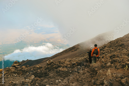 A Group of Hikers Standing on the Volcanic Rim above the clouds on a foggy day in the Alpine Desert Zone of Mount Meru, Arusha National Park, Tanzania