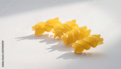 Close-up of uncooked fusilli pasta with strong shadows on a white surface