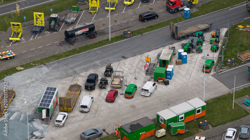 Bunnik, Utrecht, Netherlands - 16 June 2026: Aerial view of a construction site with various utility vehicles, trailers, and portable office containers parked on a paved lot.
