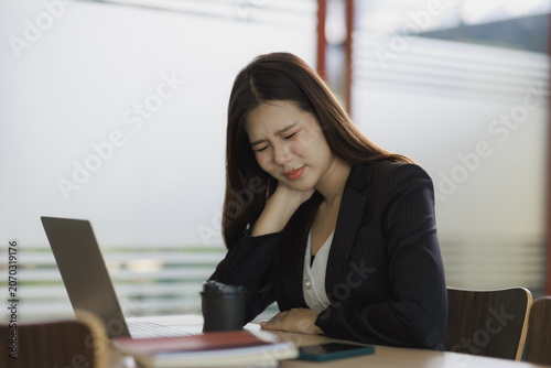 Fotografie Stressed young Asian businesswoman suffering from severe neck pain and discomfor