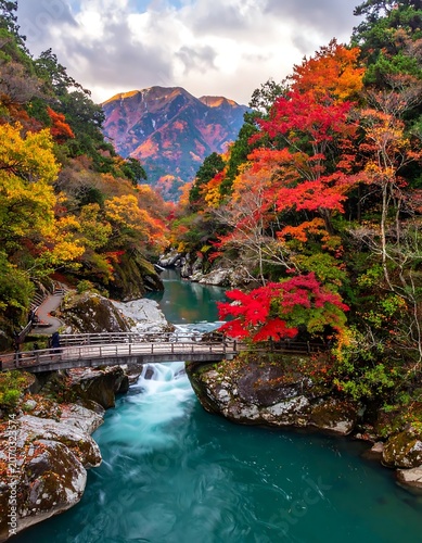 Vibrant Autumn Forest Surrounding Turquoise River and Wooden Bridge in Mountain Valley