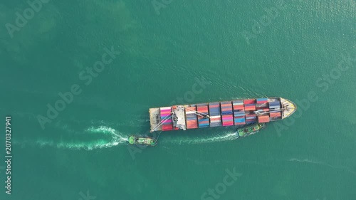 Large container ship navigates open ocean with powerful tugboat escorting it under dramatic dark sky, transporting global containers and showcasing maritime trade logistics for international commerce.