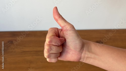 Close-up of a human hand showing a thumbs up gesture against a clean background. Positive body language concept representing approval, success, satisfaction and encouragement.