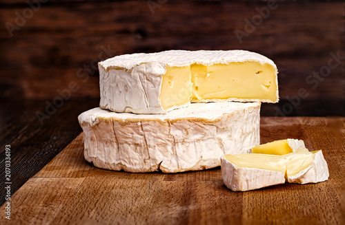 Tableau sur toile Whole and sliced Camembert cheese on rustic wooden board with dark background