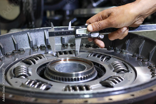 Foto Close-up of a mechanic's hand using a digital vernier caliper to check the clearance or size of a damper spring inside an automatic transmission torque converter assembly