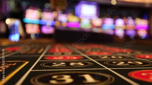 View of a roulette table layout with blurred slot machines in the background of a casino in Las Vegas, Nevada, United States.