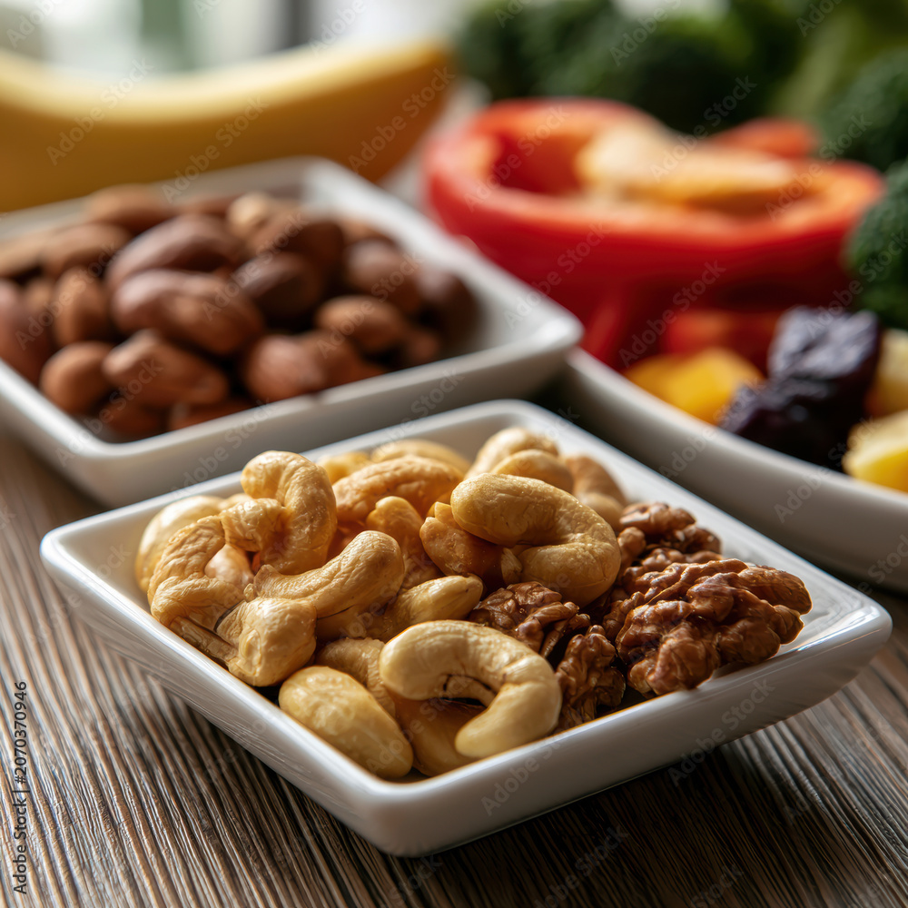 Fototapeta premium Cashew walnut almond banana red bell pepper broccoli dried fruit healthy snack fresh vegetable wooden table