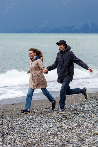 Couple runs hand-in-hand on rocky beach