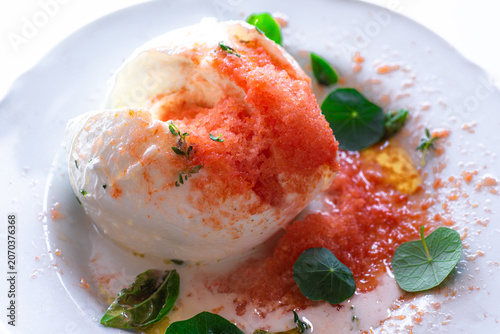 Fresh buffalo mozzarella with grated frozen tomato and herbs, gourmet Italian summer recipe 