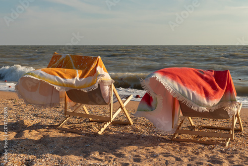 Fotografía Two sun loungers on the seashore covered with towels on a windy day
