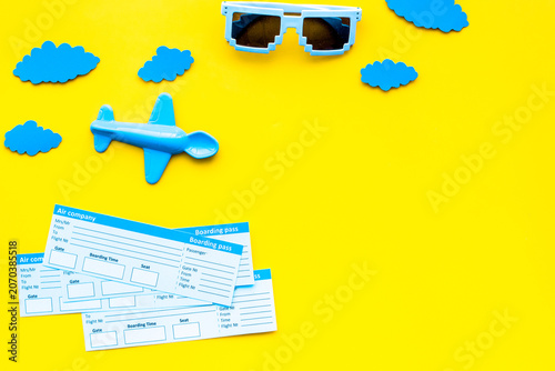 Sample of airplane ticket. Family trip with kid. Airplan toy and paper clouds. Yellow background flat lay space for text