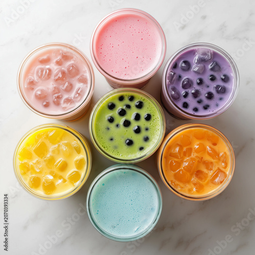 A collection of seven colorful bubble tea drinks arranged in a circle on a marble surface, a sweet treat
