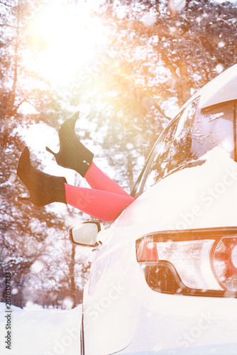 Vászonkép Snowy day with a woman's legs in red tights and black shoes hanging out of a car