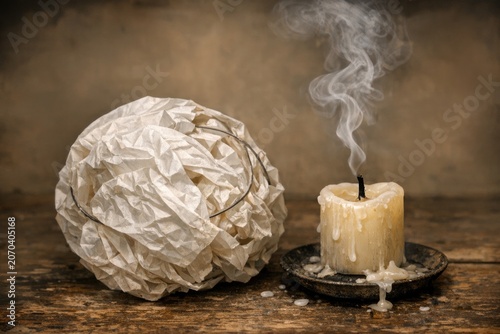 A simple setup featuring a candle and a rolled up piece of paper on a wooden table