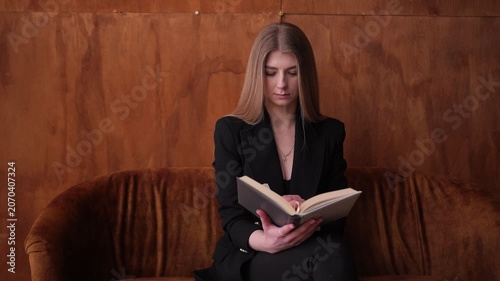 Young blonde woman reading an old book on a sofa