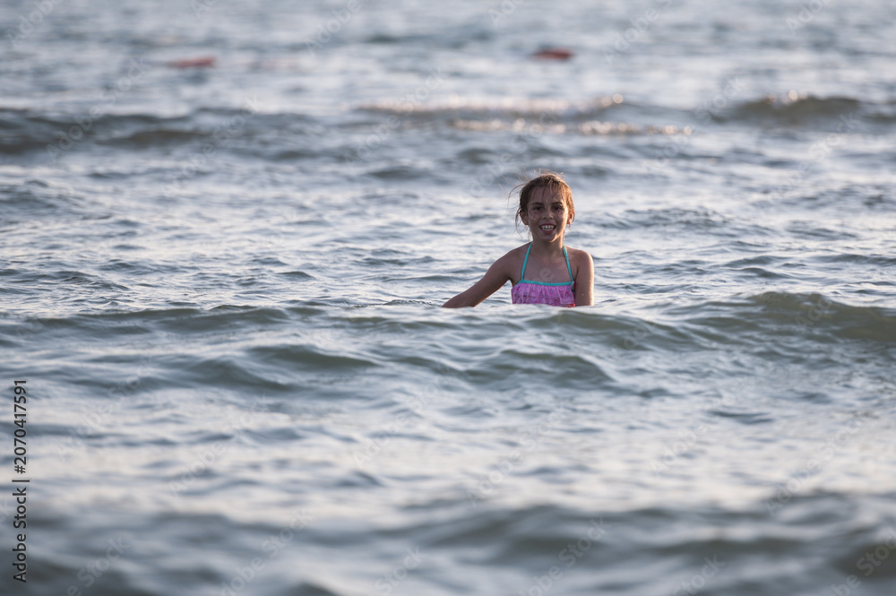 Fototapeta premium Happy child smiling in ocean water during summer vacation